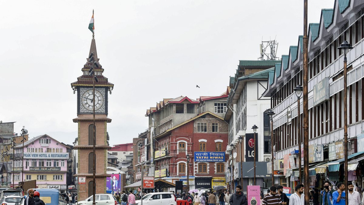 Rain lashes Srinagar as people walk through Lal Chowk