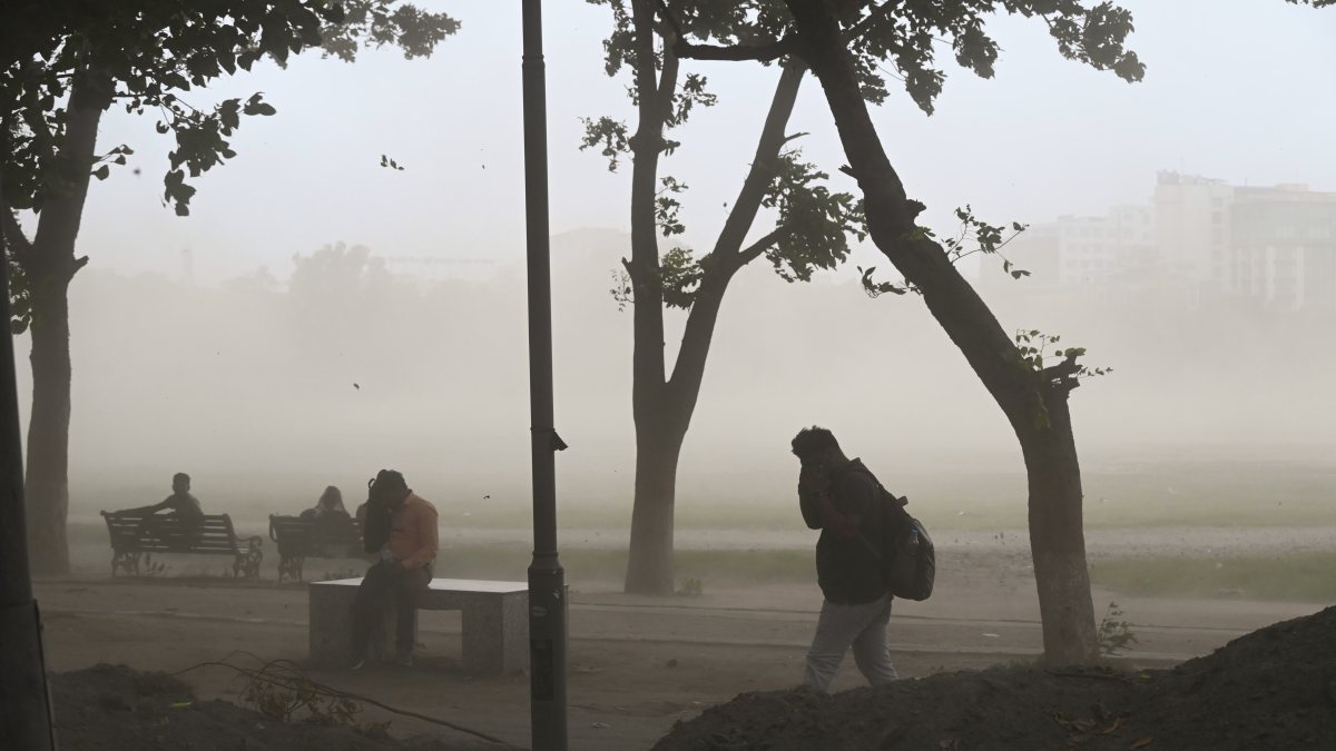 People cover their eyes from dust storm, in Patna on Thursday.