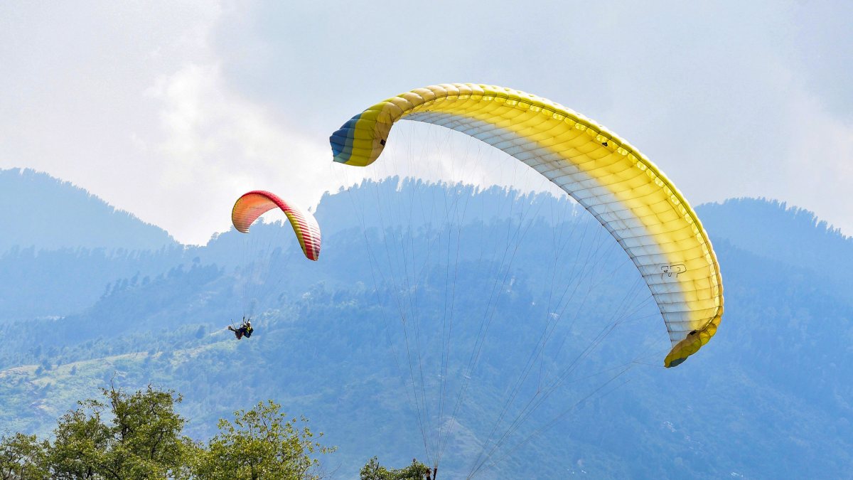 Tourists paraglide over scenic Solang Valley in Manali