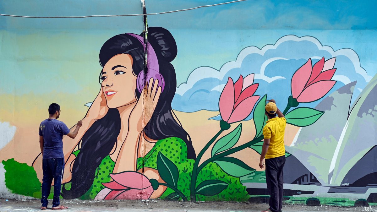 Artists paint a colourful mural on a wall, in New Delhi on Friday.