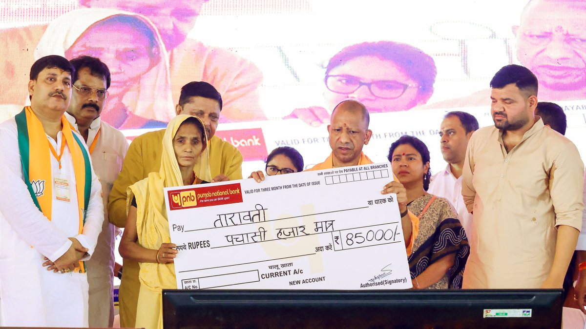 Uttar Pradesh Chief Minister Yogi Adityanath presents a cheque to a beneficiary…