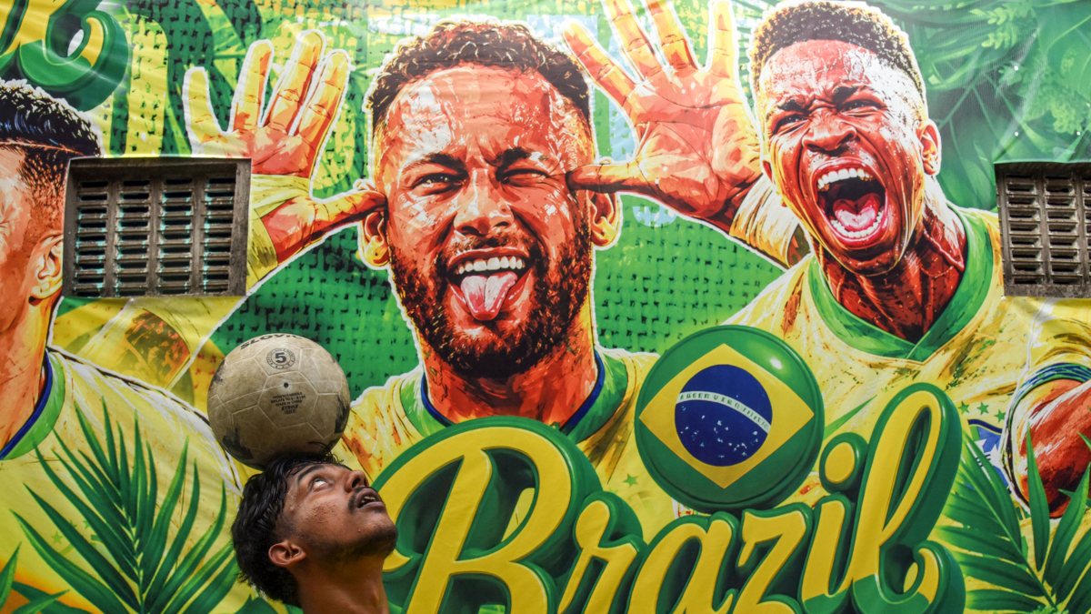 Young boy balances football in front of Brazil mural in Howrah