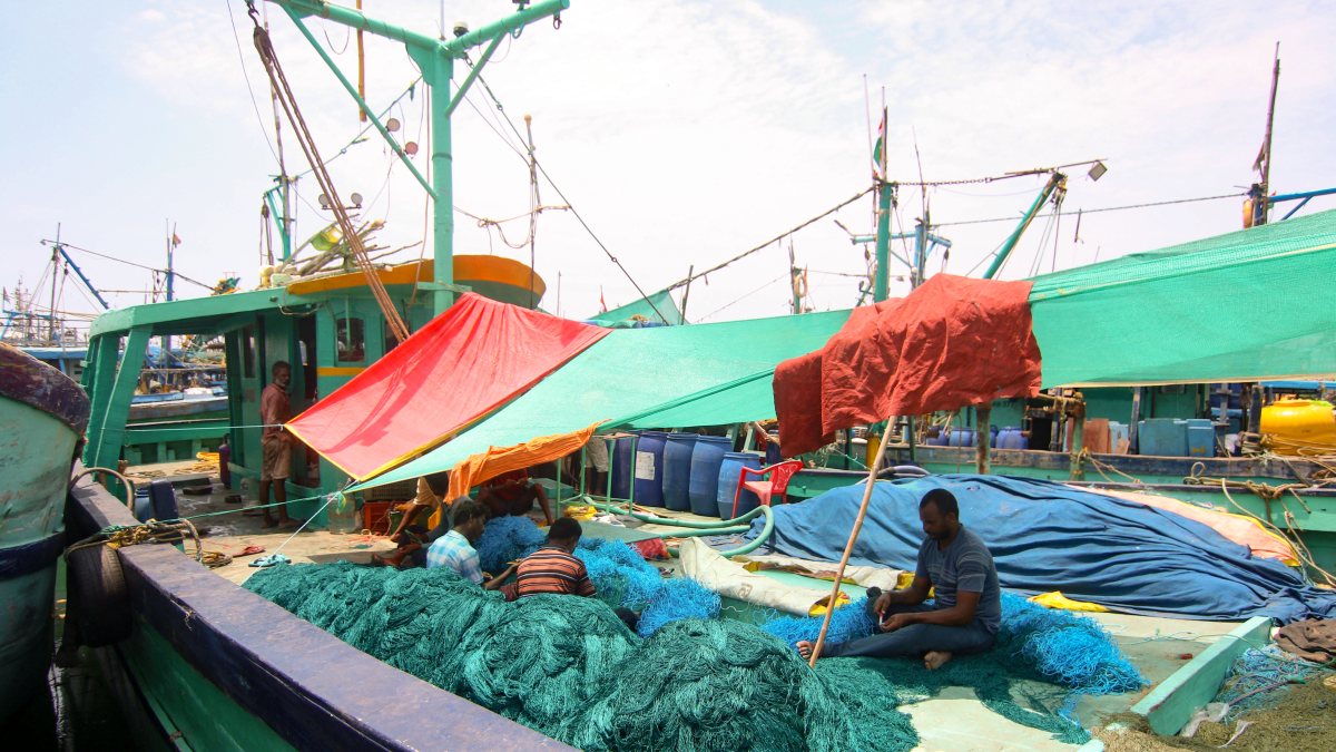 Fishermen repair nets at Kasimedu fishing harbour in Chennai