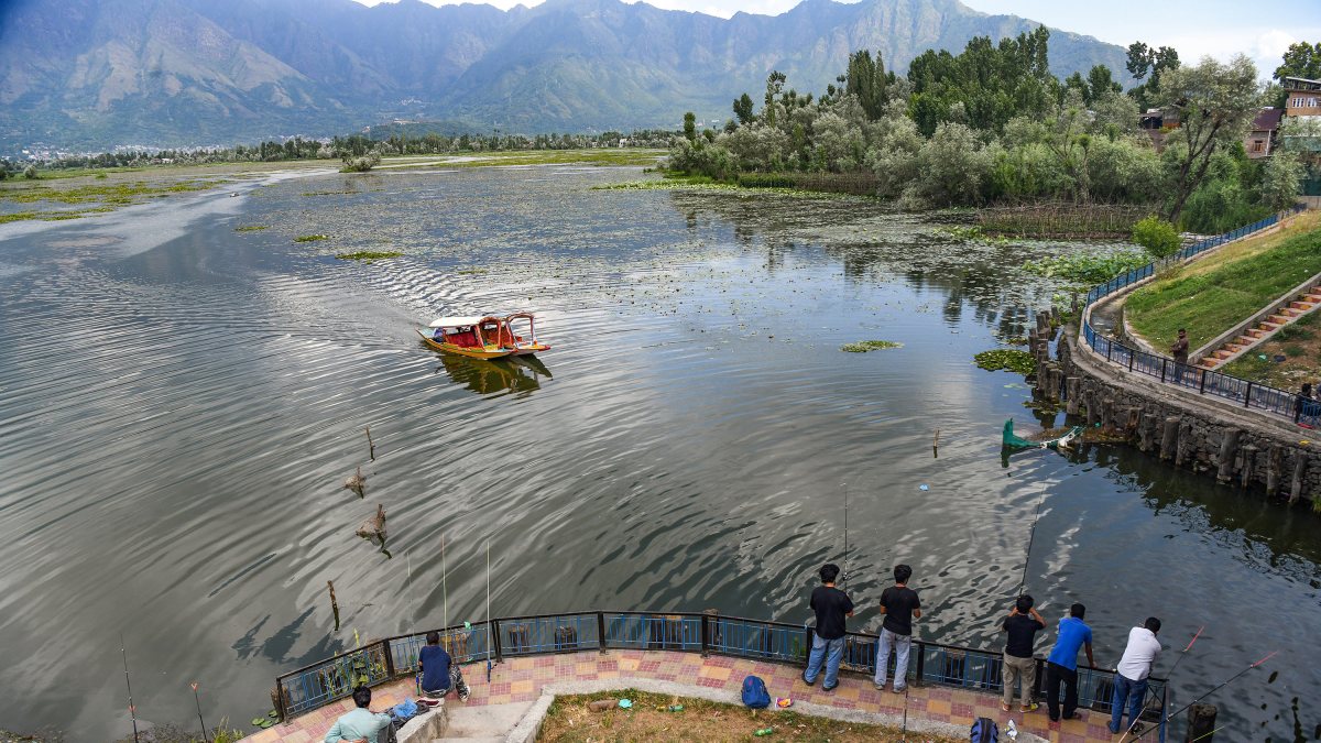 People fish at Nigeen Lake as tourists enjoy shikara ride