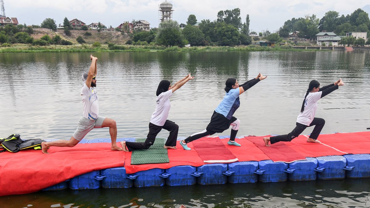 People perform Yoga on a pontoon platform at Pokhribal Lake ahead of the…
