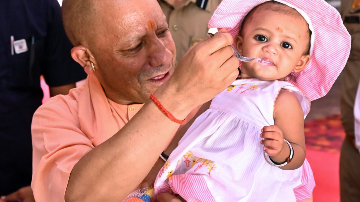 Uttar Pradesh Chief Minister Yogi Adityanath feeds a child during his visit to…