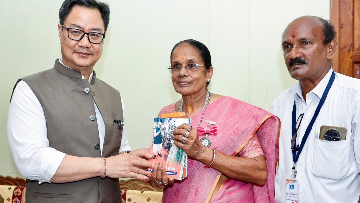 Union Minister Kiren Rijiju presents a booklet to Padma Shri awardee K…