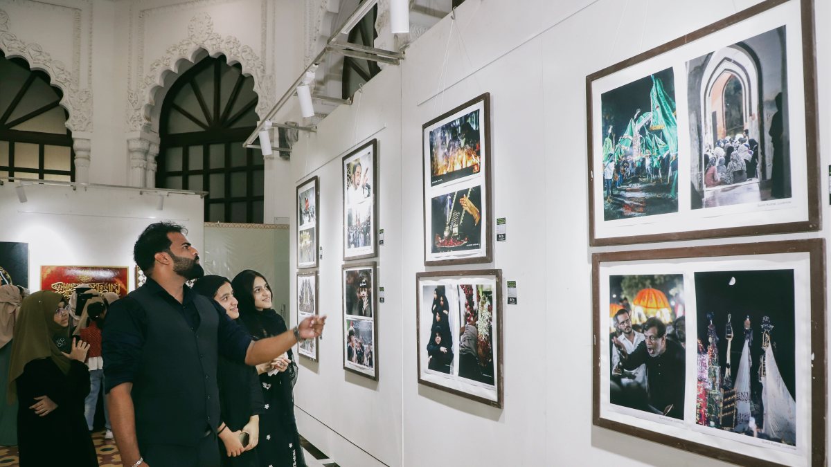 Visitors view photographs and artworks on the theme of Muharram at the 18th…