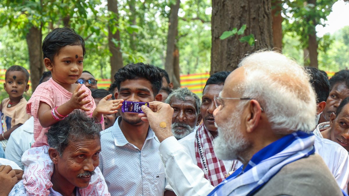 Prime Minister Narendra Modi offers a chocolate to a child during his visit to…