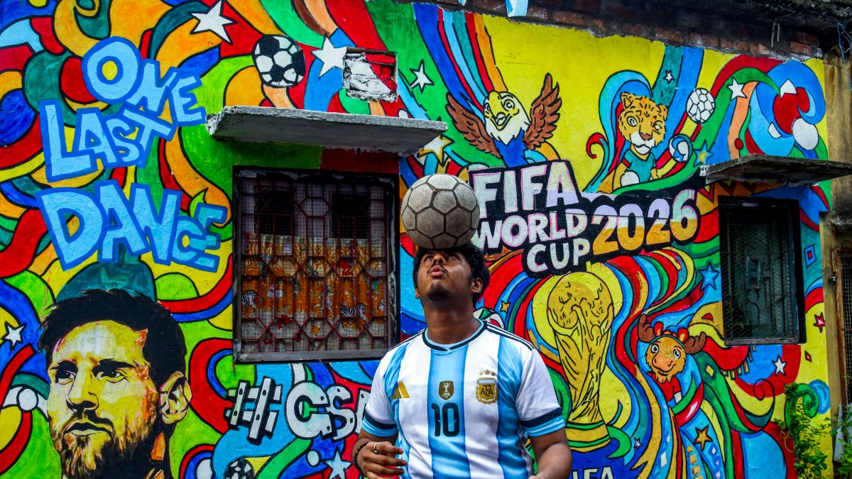 Argentine fan balances football beside Messi mural in Kolkata