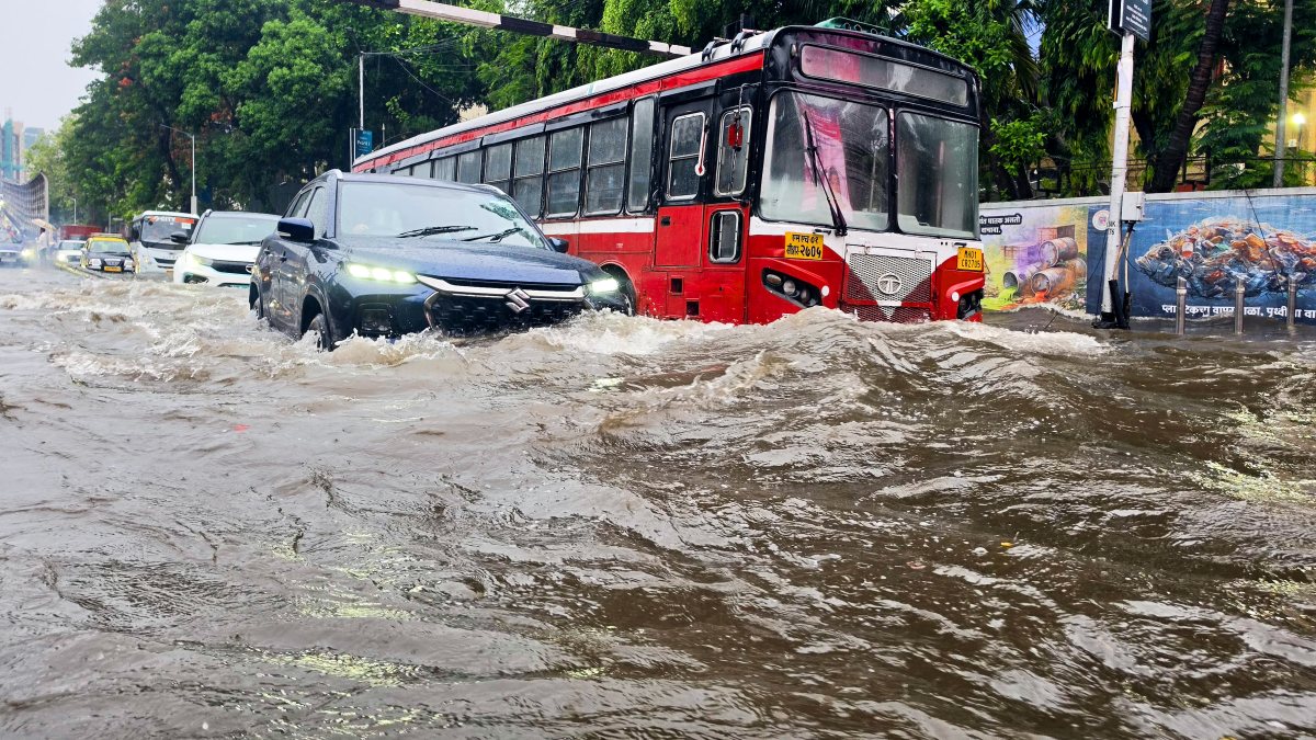 Vehicles wade through a waterlogged road amid heavy rainfall, in Mumbai on…