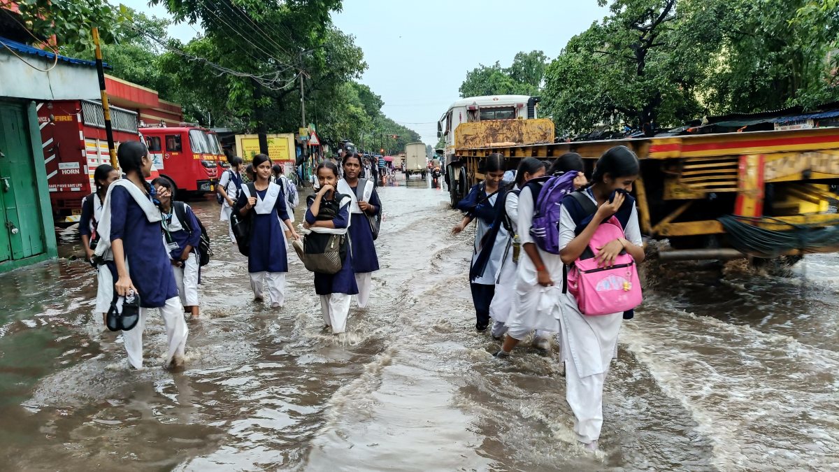 School girls wade through waterlogged Kolkata road after heavy rain