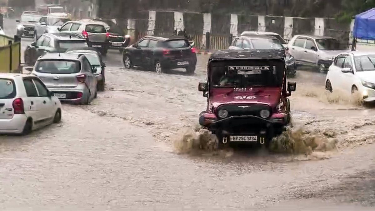 Commuters wade through a waterlogged street at Dhalli area, in Shimla on…