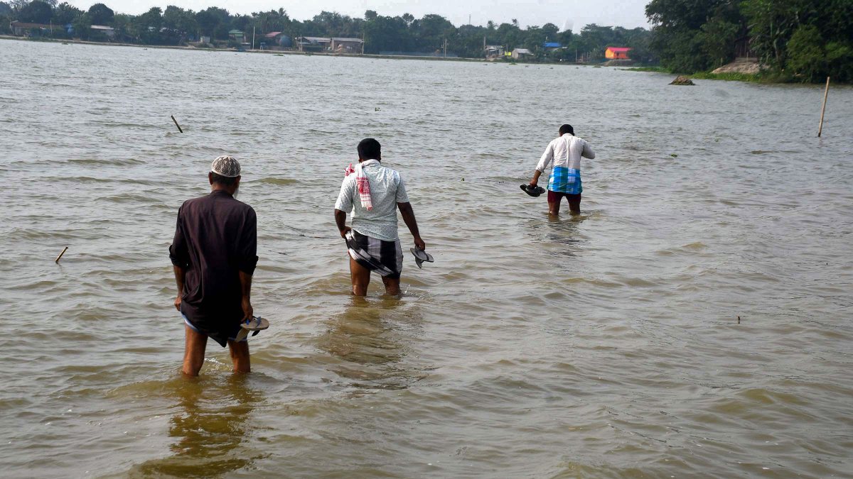 Villagers wade through flood water in Morigaon's Sildubi village