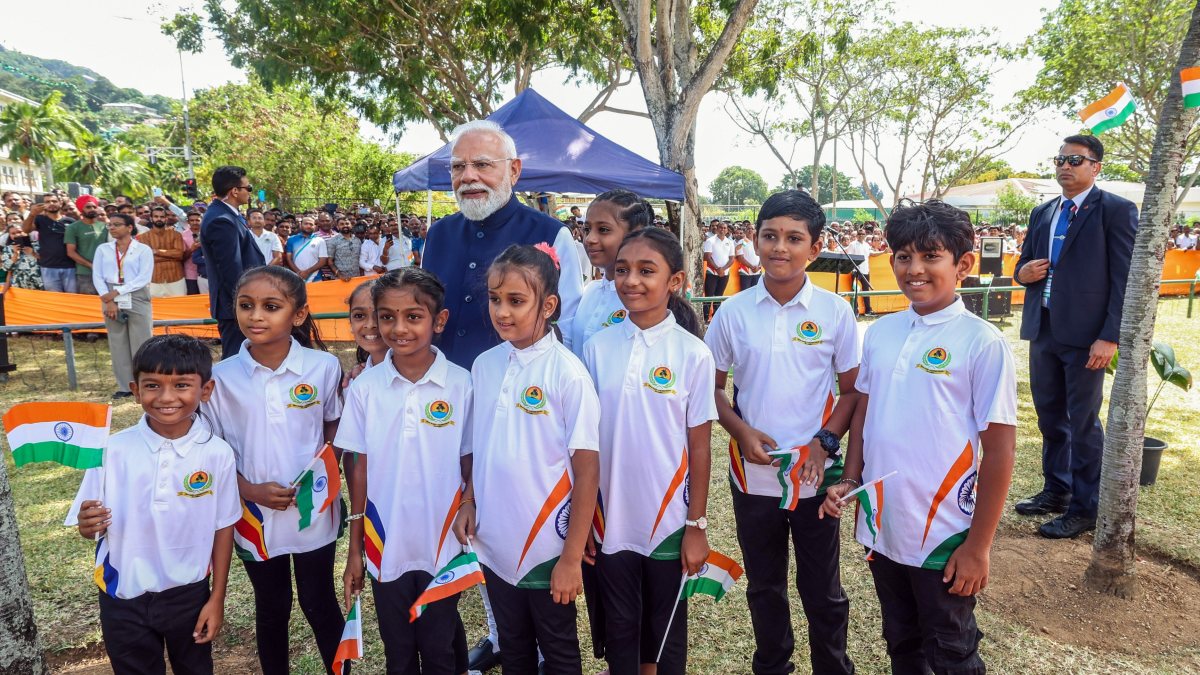 Prime Minister Narendra Modi in a group photograph with children as he visits…