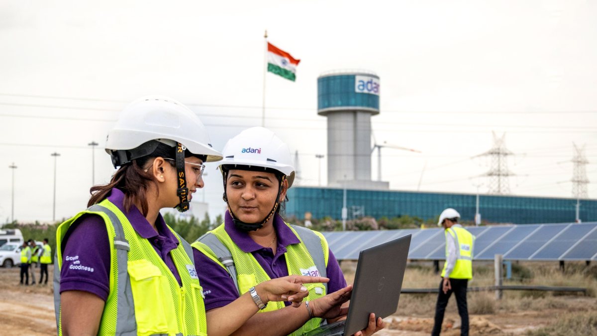 Women engineers examine a laptop at Adani Green Energy's solar power plant…