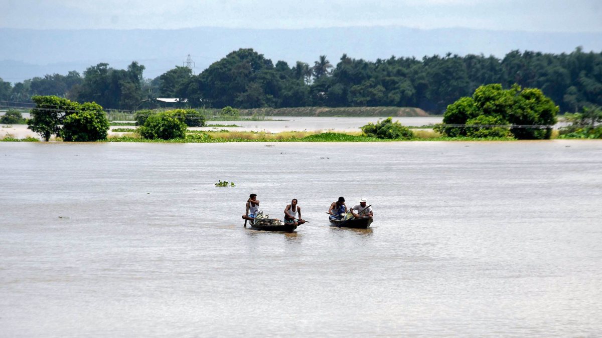 Villagers navigate floodwaters by boat in Morigaon