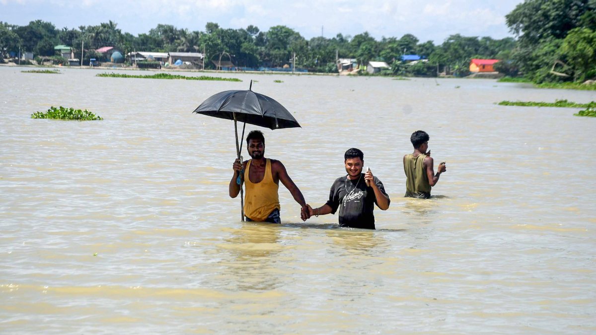 Villagers wade through floodwater in Morigaon's Mayang village