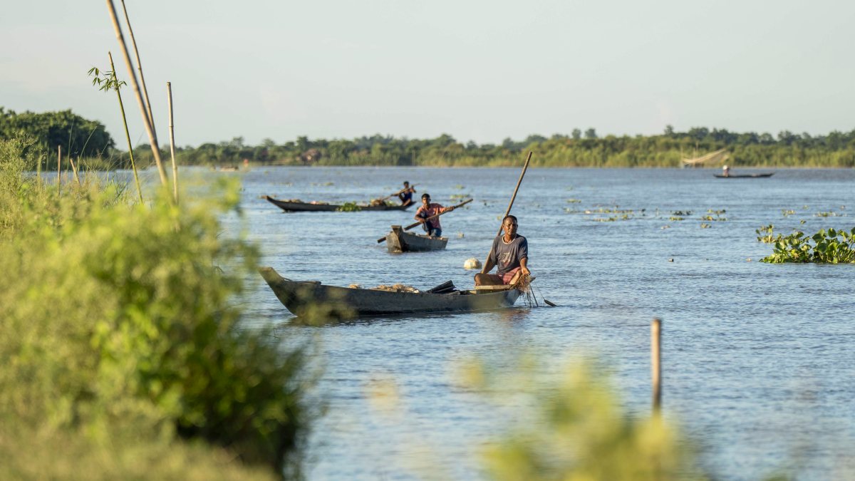Fishermen row boat in Dhansiri River on hot summer day