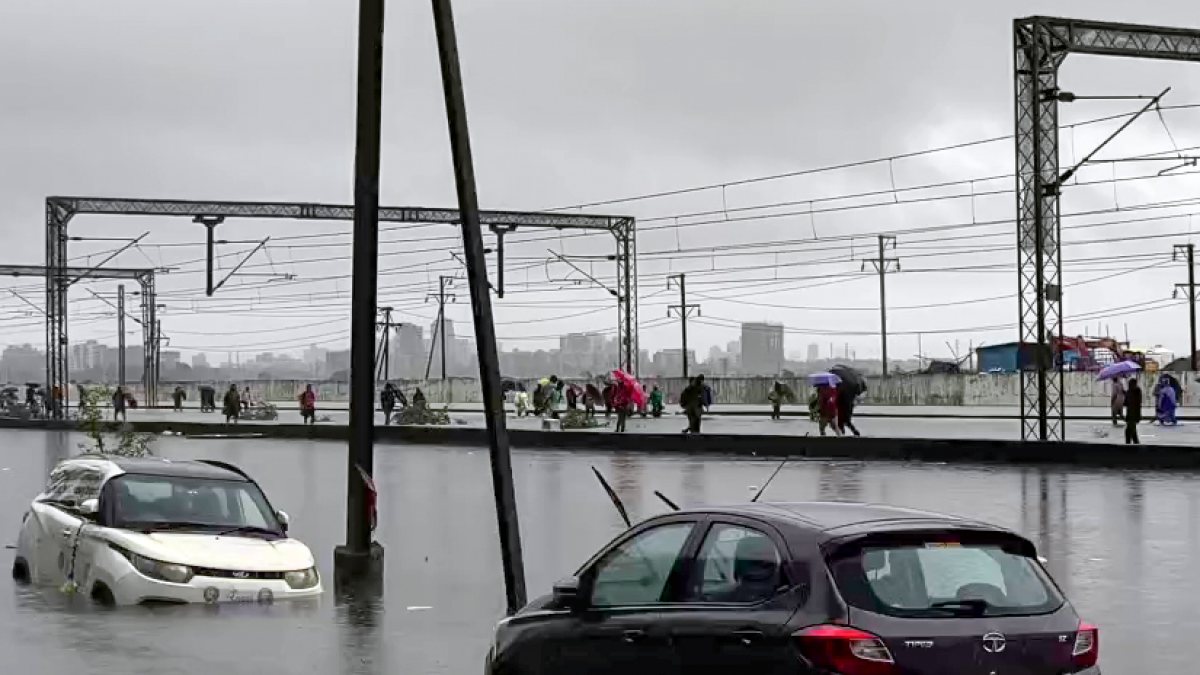 Mumbai commuters walk along waterlogged tracks near Vasai station