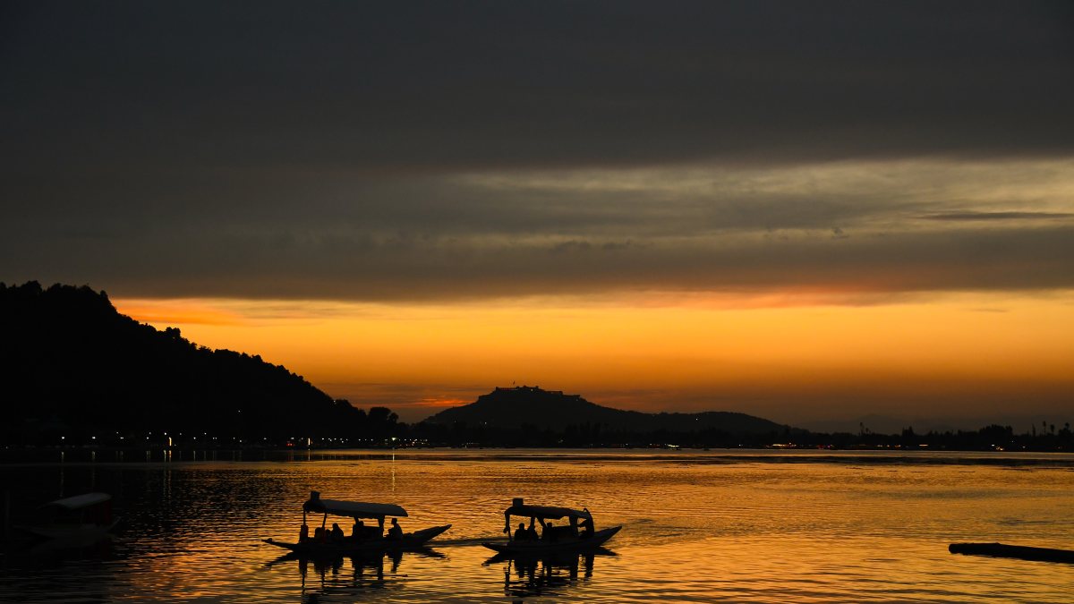 Boatmen row across Dal Lake at sunset in Srinagar
