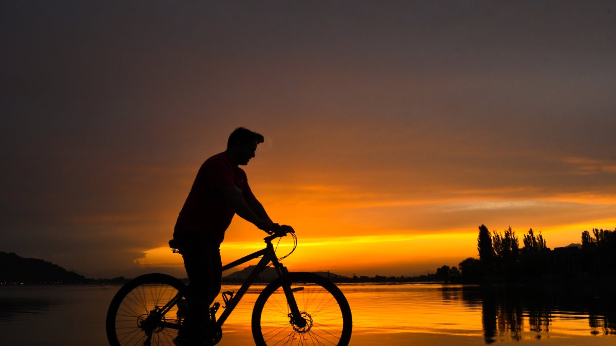 A cyclist rides along Dal Lake during sunset, in Srinagar on Monday.