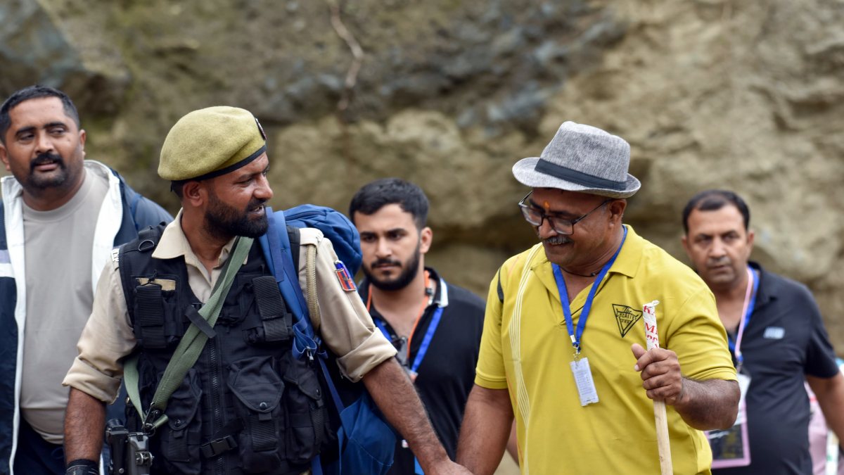 Security official aids pilgrim on Amarnath Yatra mountain trail