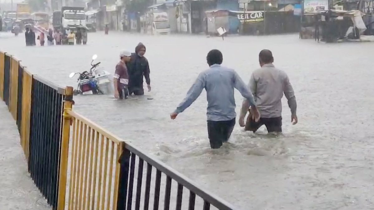 People wade through waterlogged road in Surat amid heavy rain