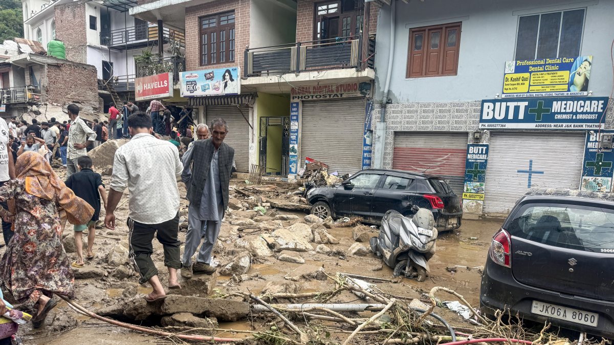 People walk over flood debris in Doda