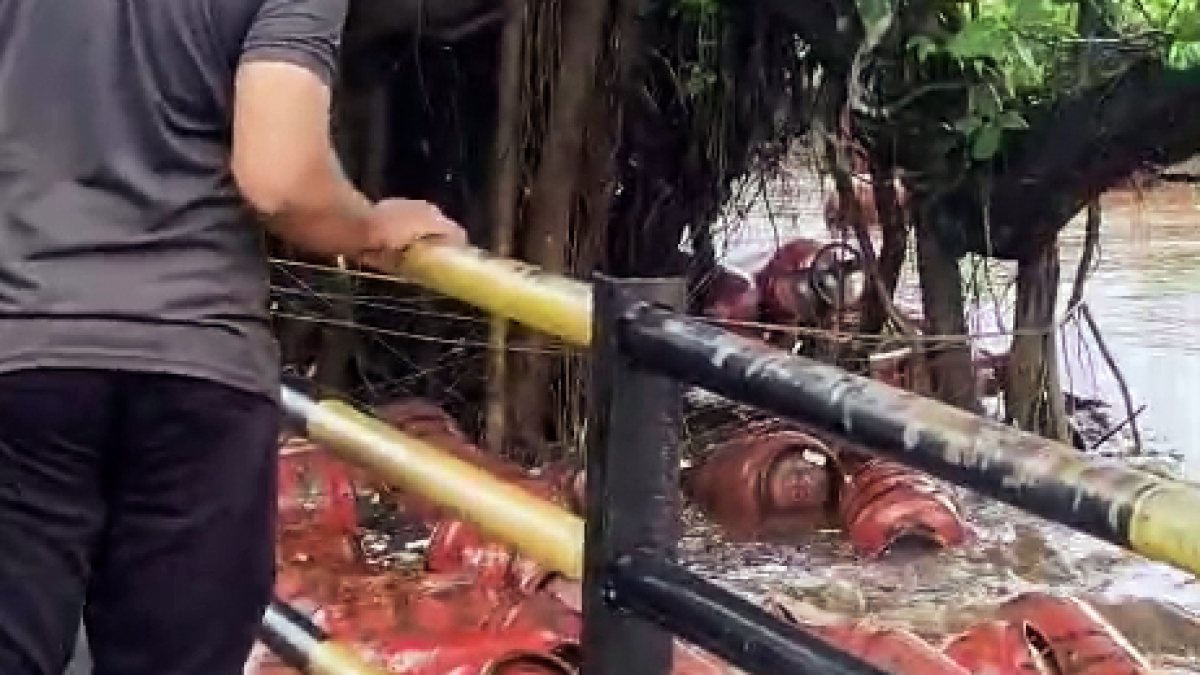 Floodwaters wash away LPG cylinders from a bottling plant into the Patalganga…