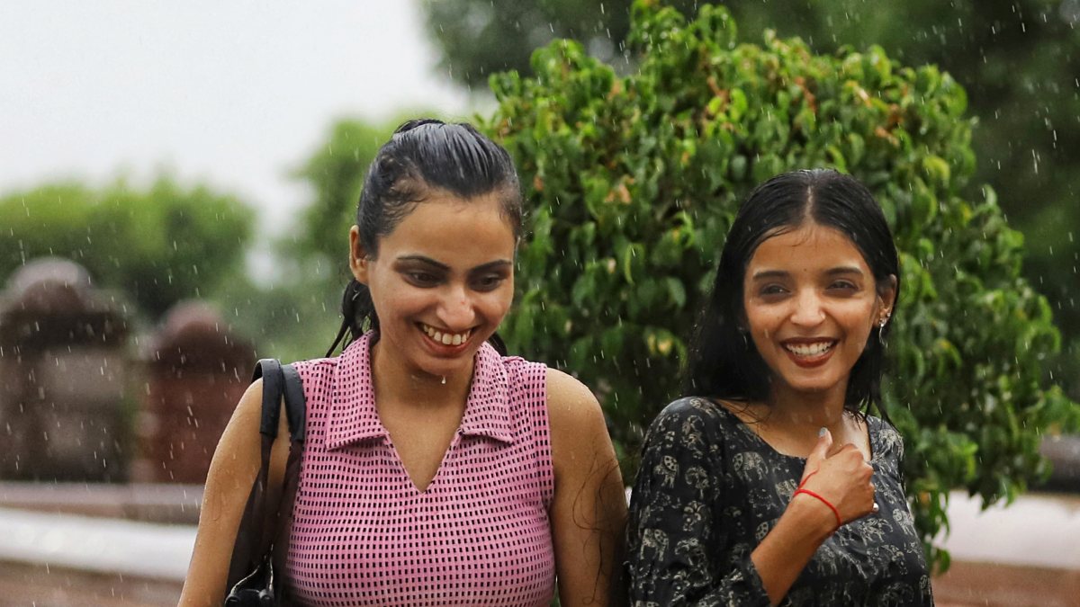 Women enjoy rainy weather, in Lucknow on Thursday.