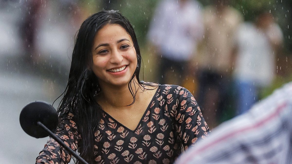 A woman rides a bike amid rainy weather, in Lucknow on Thursday.