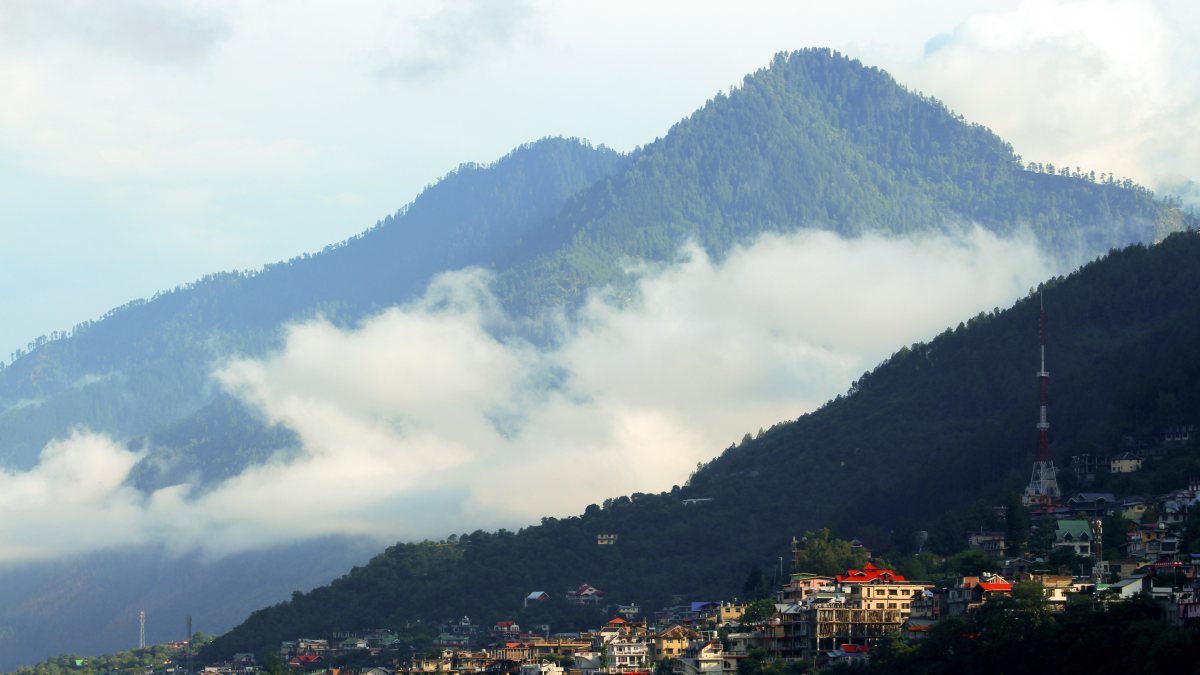 A view of the dense clouds and mist draping hillside of the valley following…