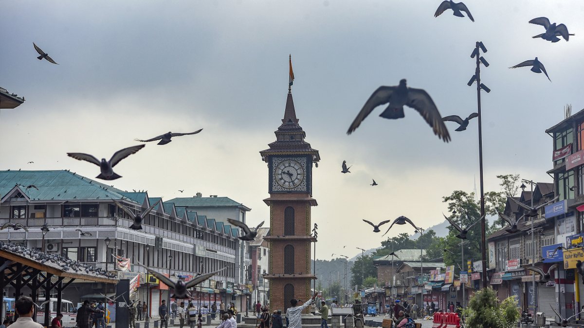 Flock of pigeons flies near clock tower at Lal Chowk in Srinagar