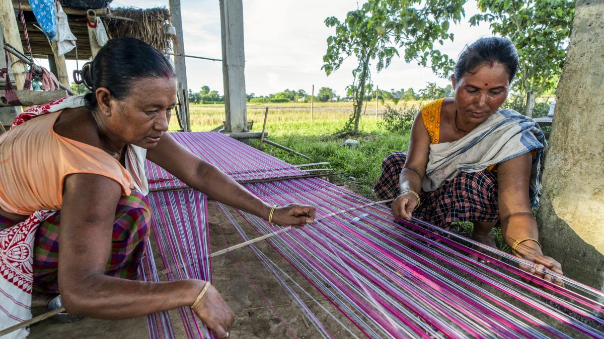 Tribal women weave threads on traditional handloom in Golaghat