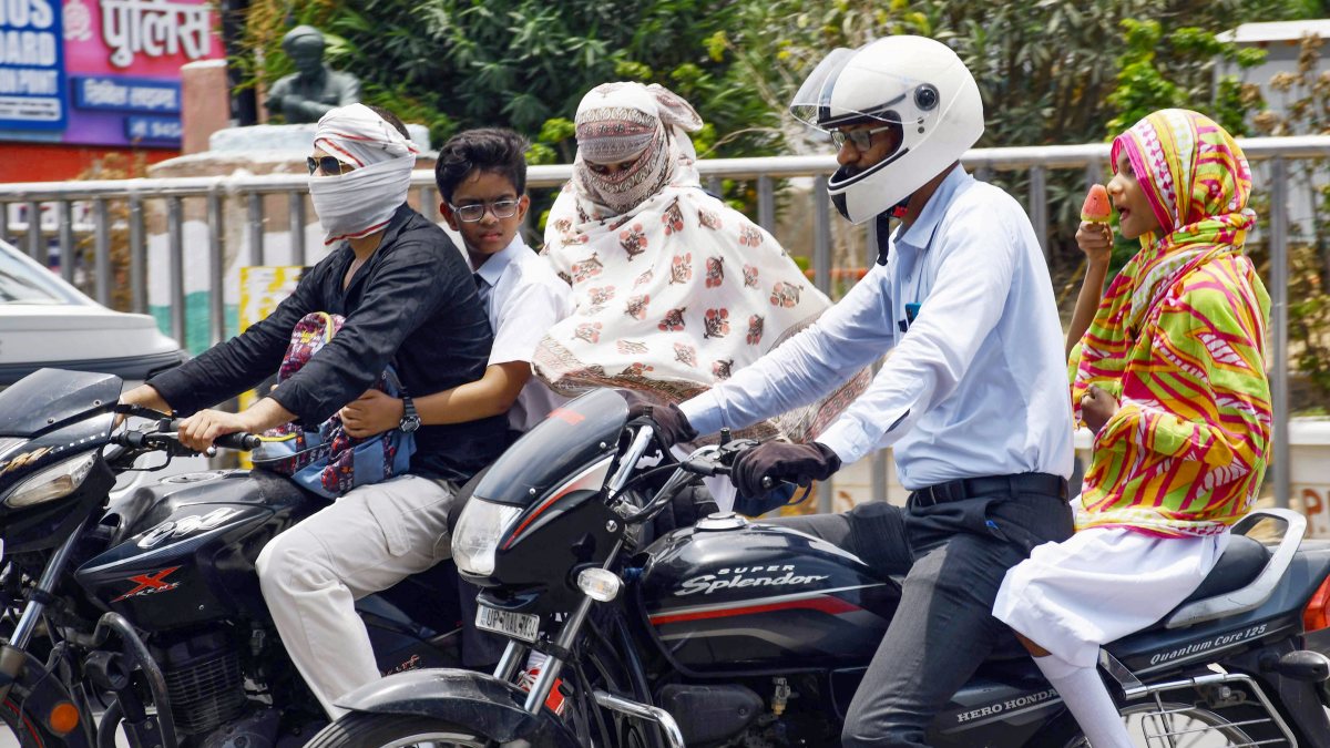 Commuters cover up with scarves on a hot afternoon in Prayagraj