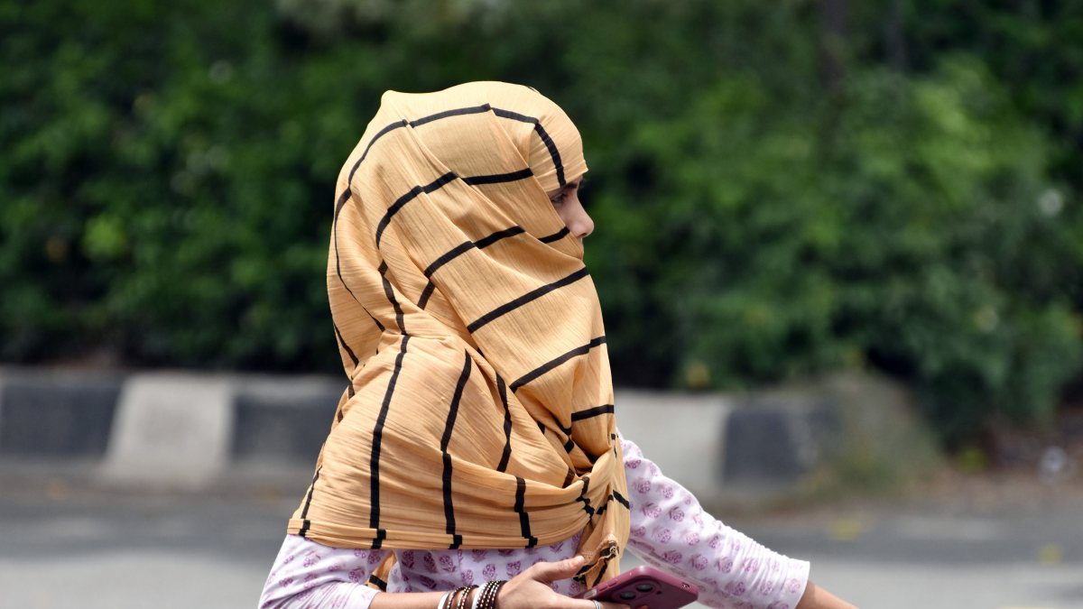 Woman shields from humid heat wave with scarf in Ghaziabad
