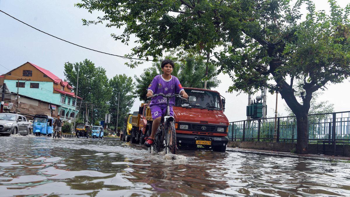 Vehicles and cyclists wade through waterlogged Srinagar streets