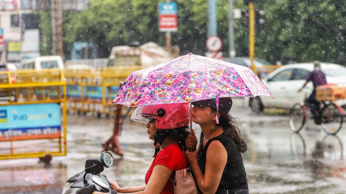 Women use umbrella while riding scooty in Lucknow rain