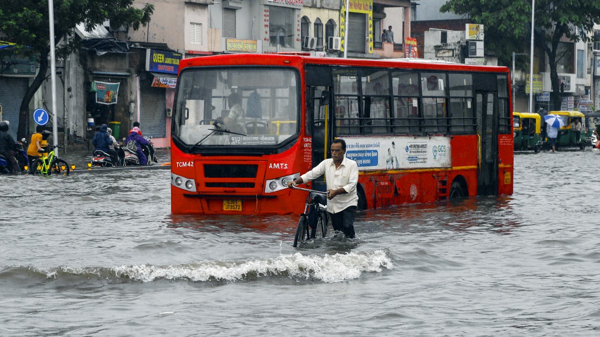 Man with bicycle wades through waterlogged road in Ahmedabad