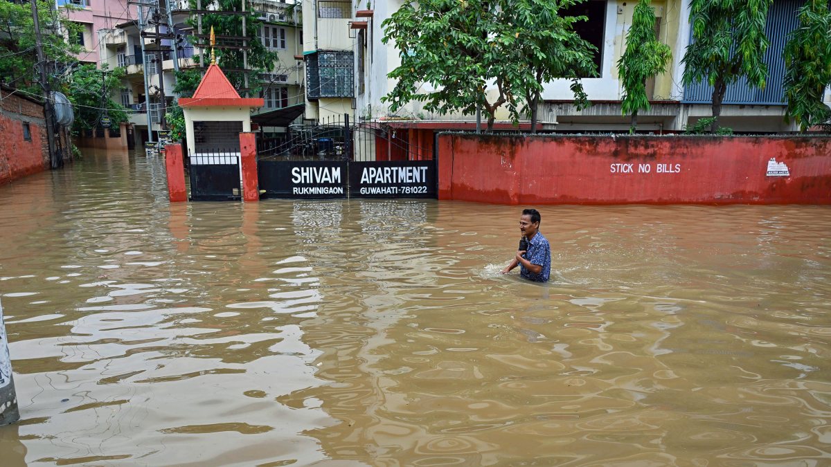 A man wades through the waterlogged road following heavy rainfall, in Guwahati…
