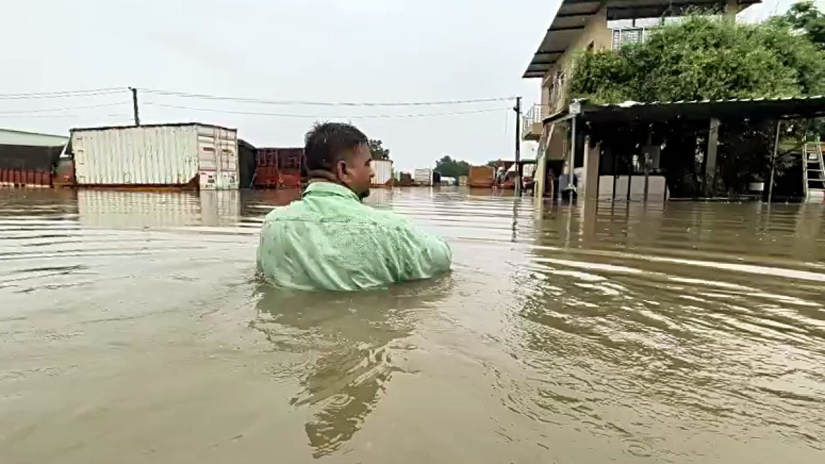 A man wades through a waterlogged road after heavy rainfall near Sanathal Cross…