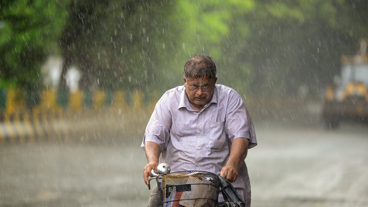 A commuter on a cycle makes his way through a rain-slicked road amid rainfall…