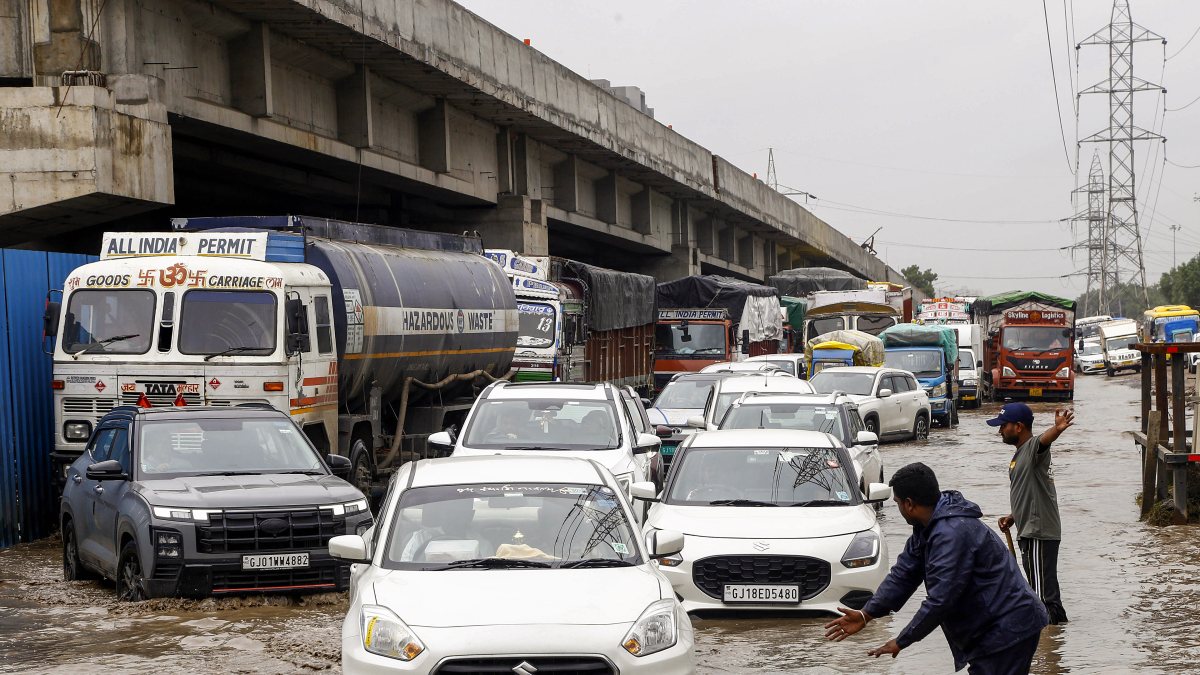 Security personnel help vehicles through waterlogged Ahmedabad road