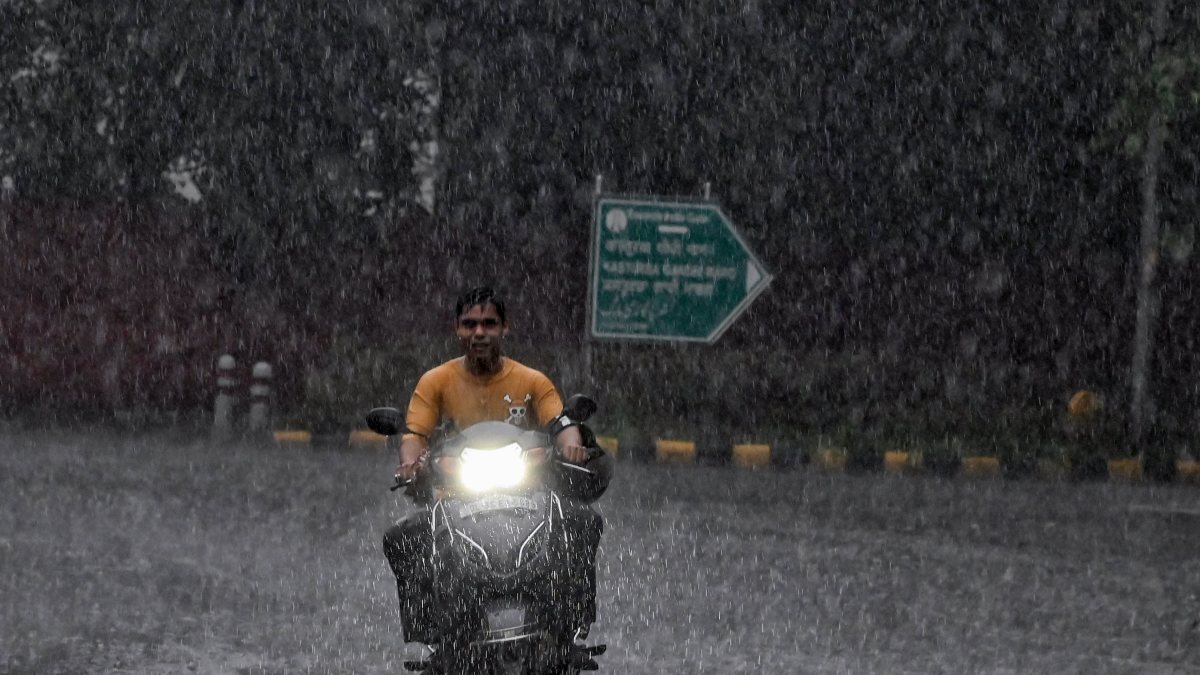 Scooter rider navigates Delhi streets amid heavy monsoon rain