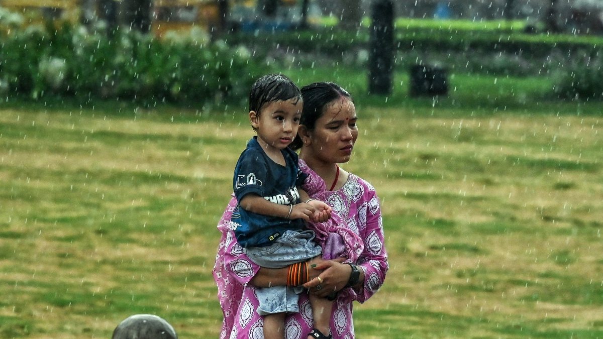 Woman and child walk through rain at Kartavya Path
