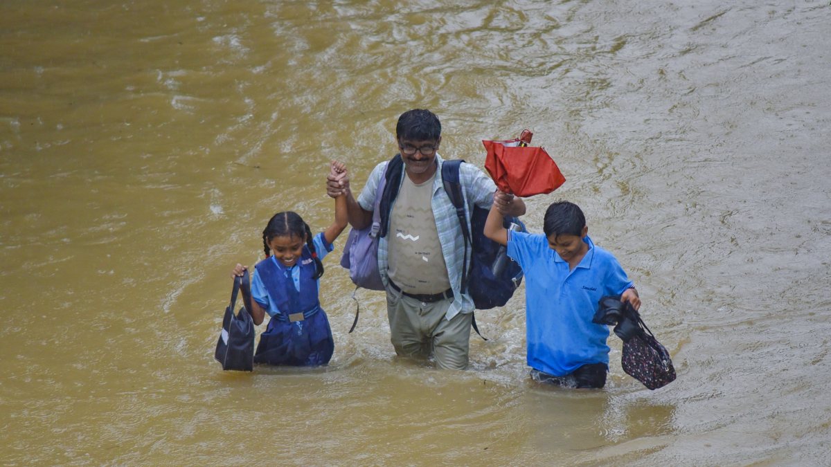 Man wades through waterlogged road with children in Nagpur