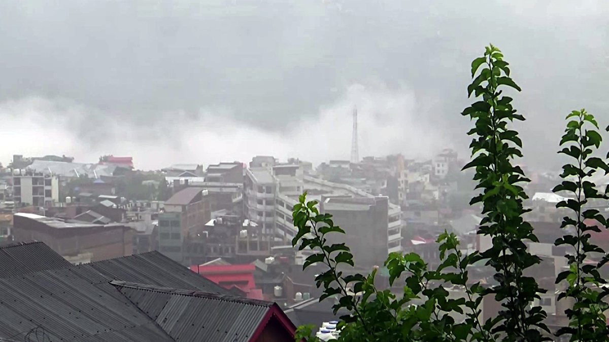 Mist-covered buildings amid heavy rain in Doda