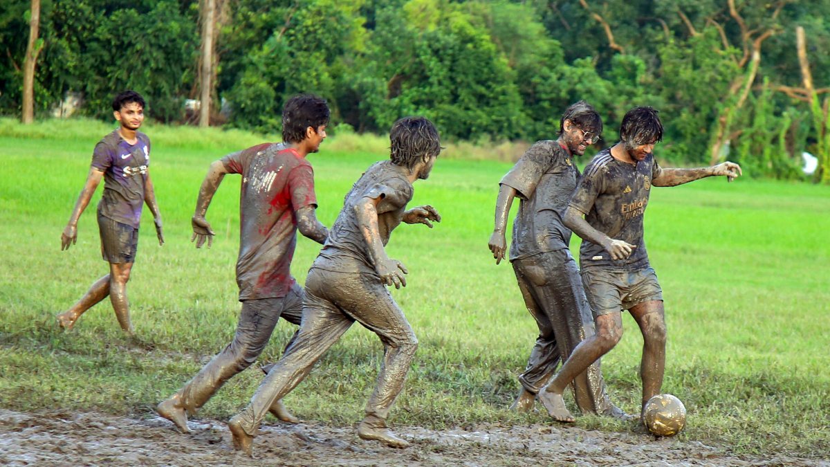 Boys play mud football on rain-soaked Kolkata ground