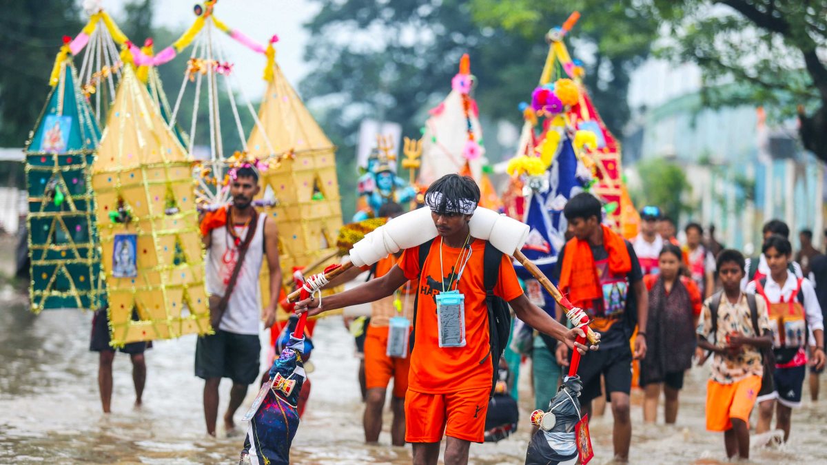 Devotees carry Ganga water through flooded streets during Kanwar Yatra